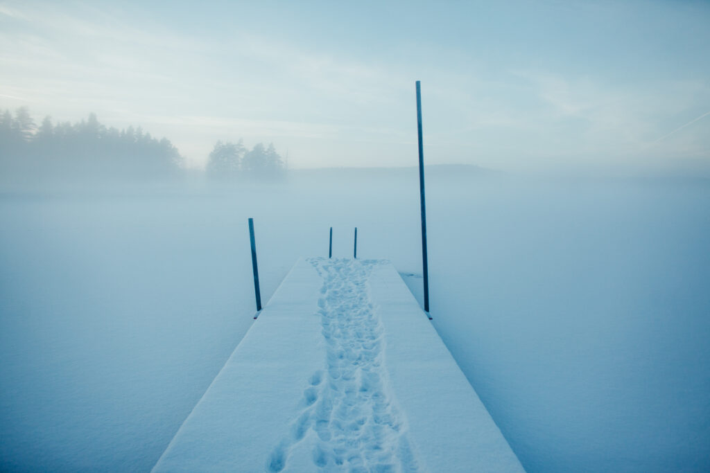A snowy jetty leading into a frozen lake.