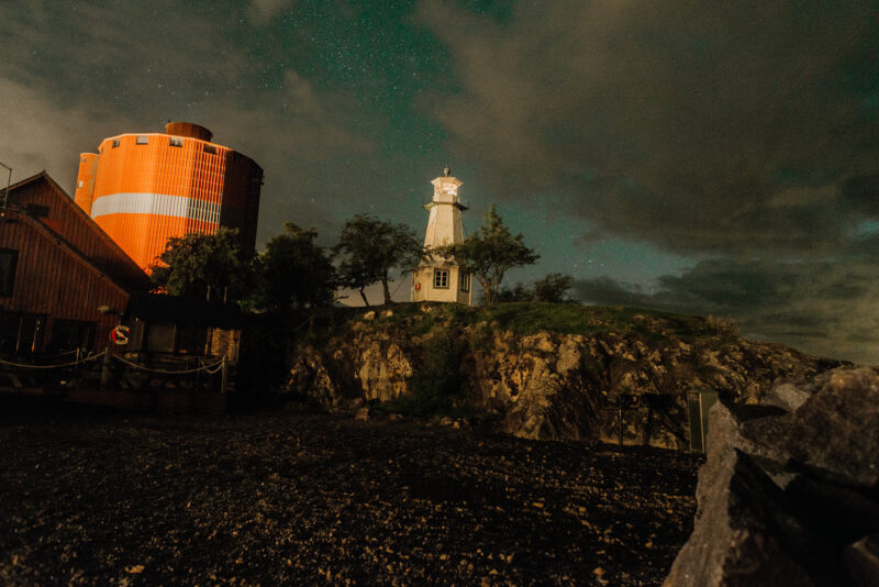 A silo and a lighthouse beneath a starry sky