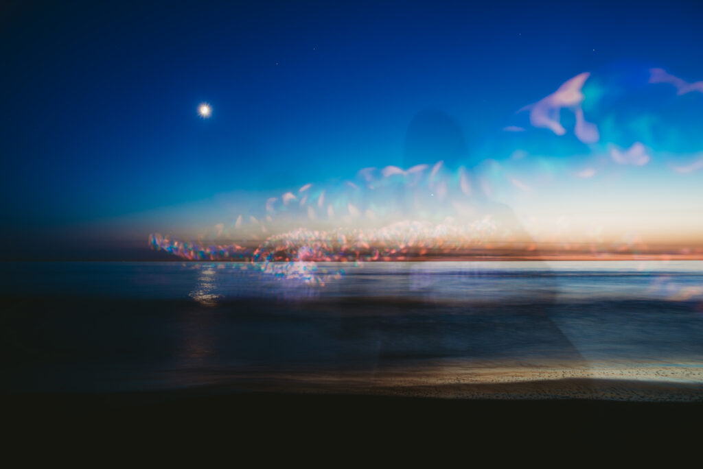 Abstract shadows and lights at the beach at night. A moon is seen in the background.