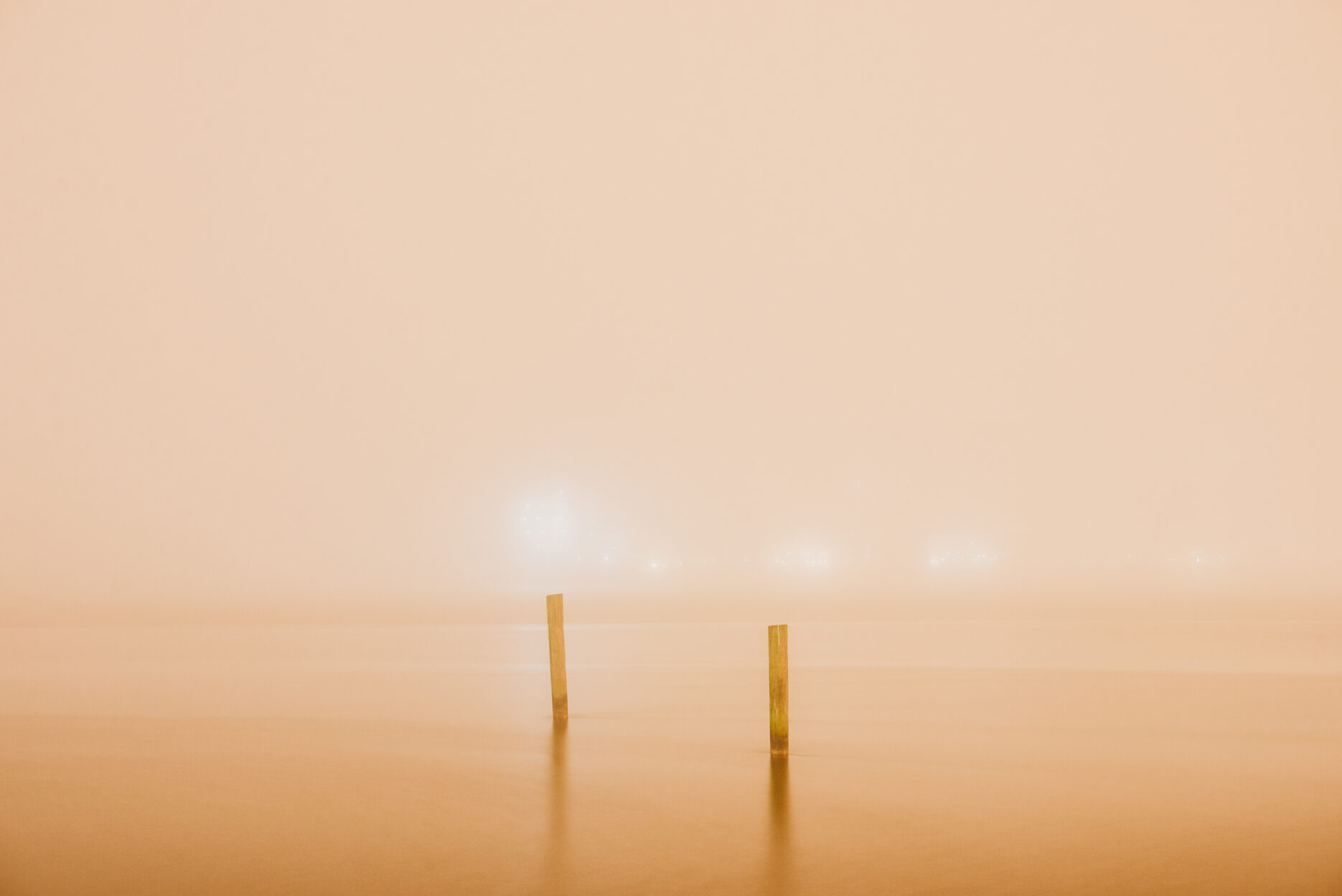 Two poles in a river during a foggy night