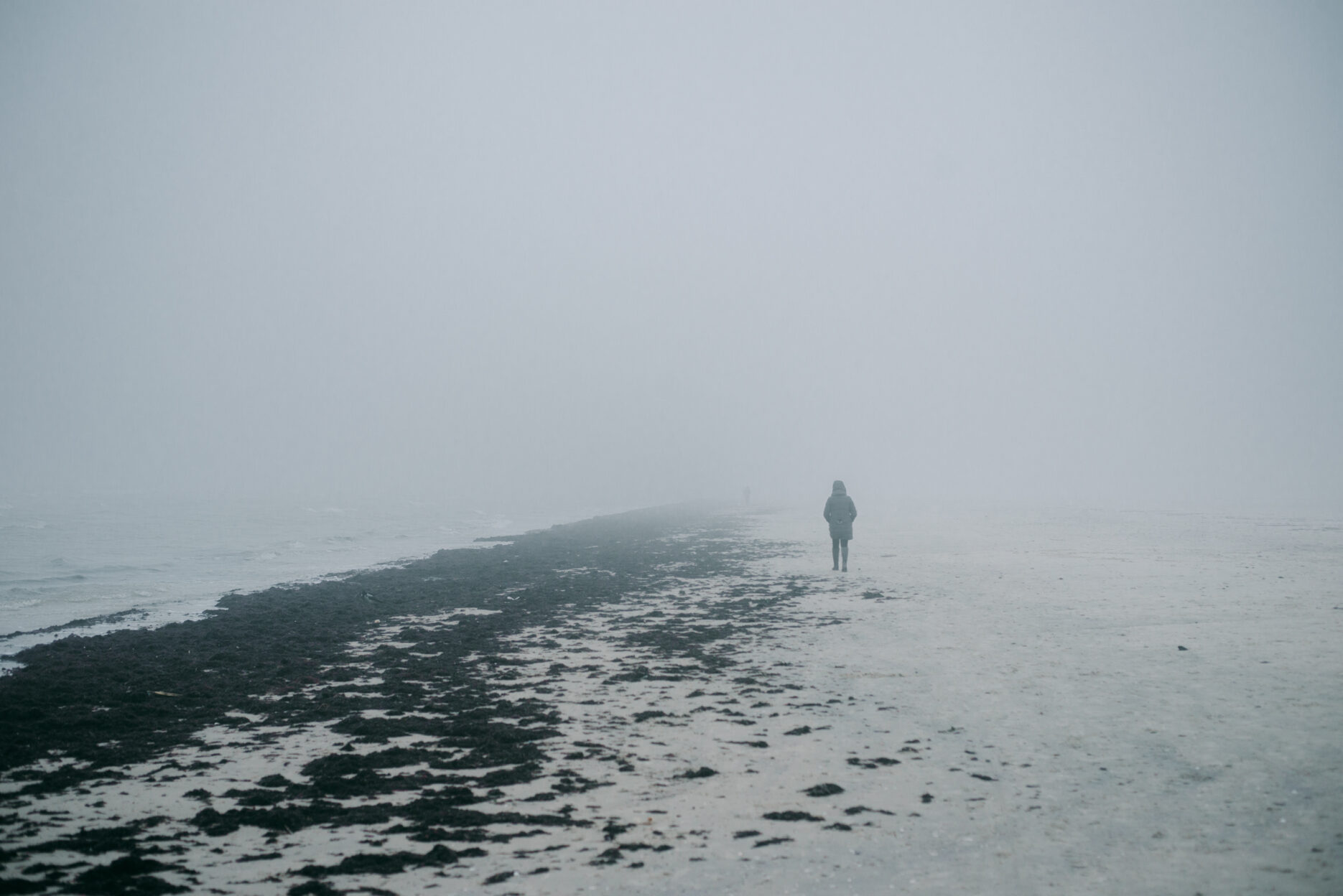 Person walking on a foggy beach