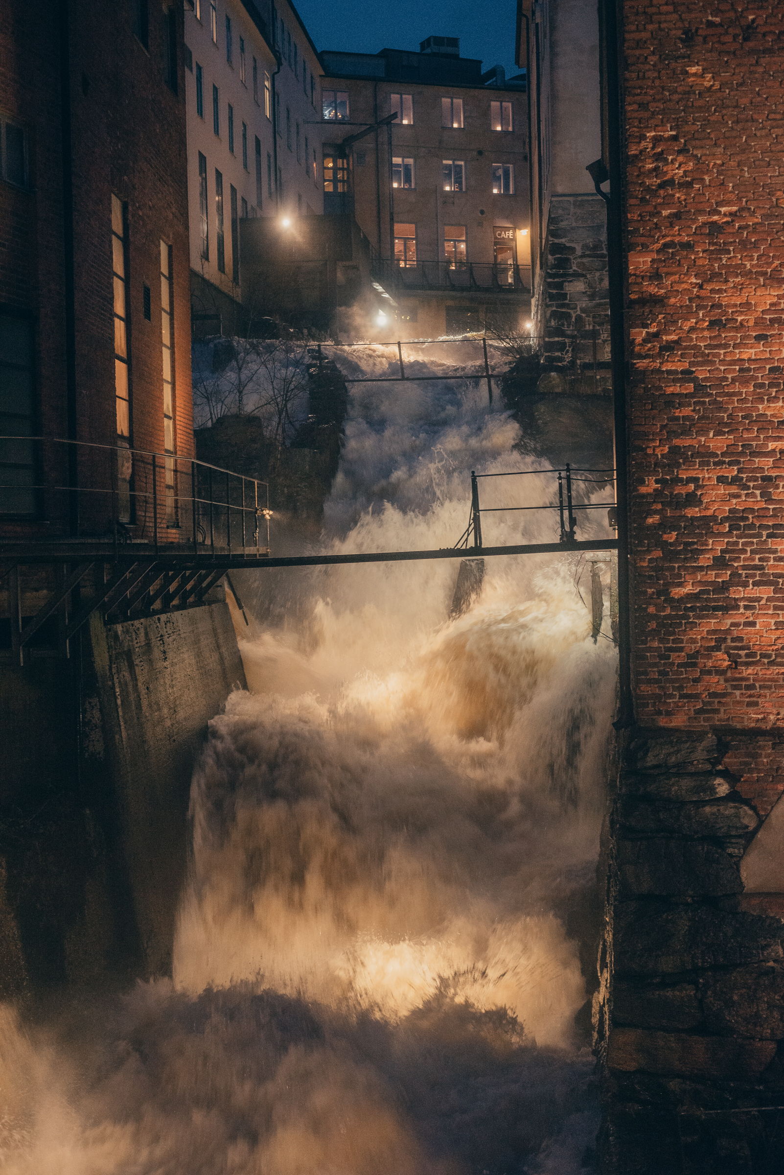 A steep water fall between old industrial buildings