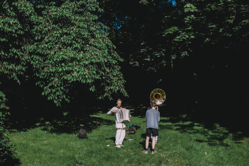 A man with an accordion and a man with a tuba standing in the grass