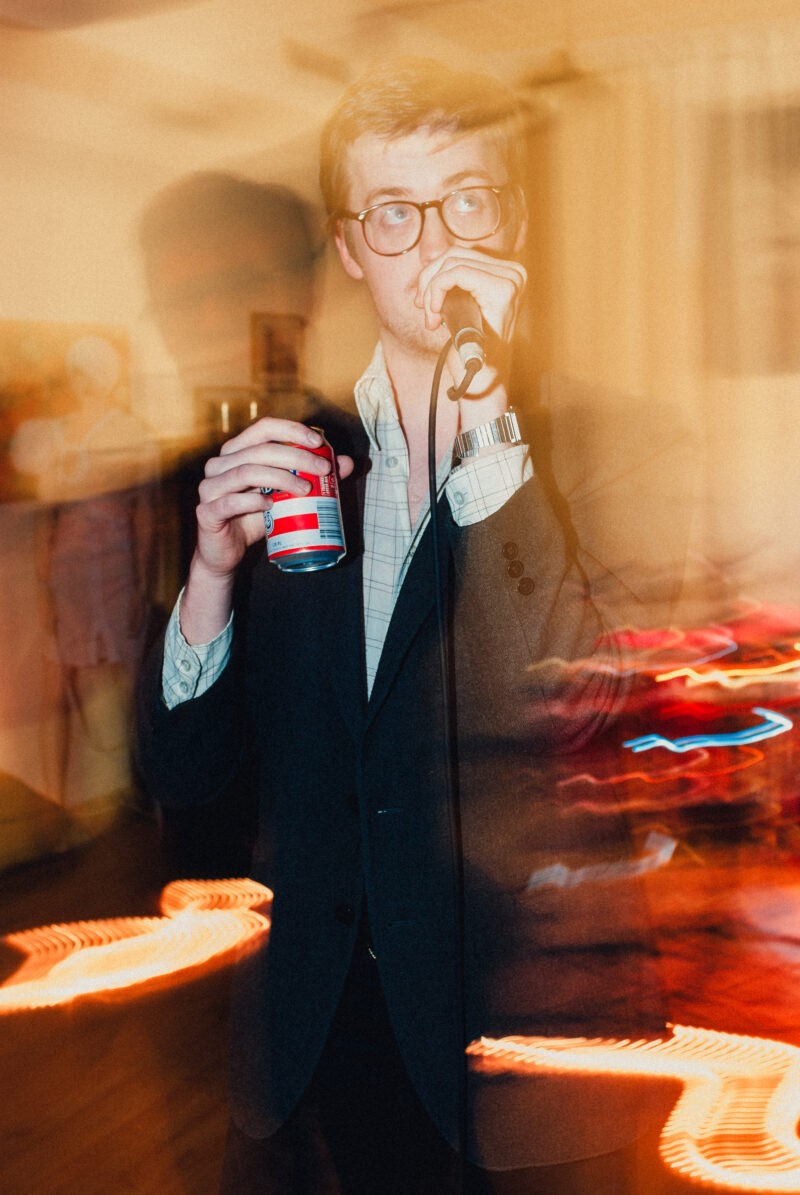 Musician James Ausfarth singing while holding a beer can