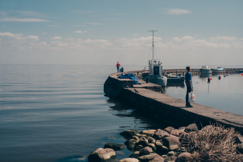 A stone pier and a few boats. A couple of people looking out over the Baltic Sea.
