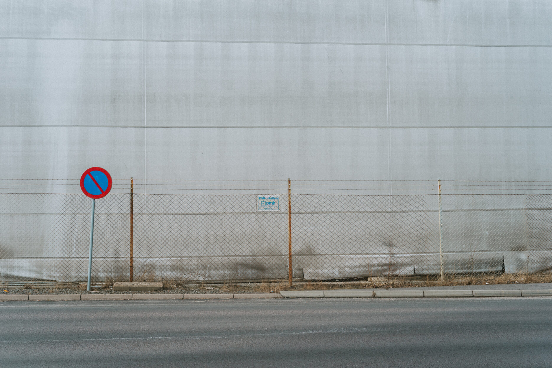 Traffic sign and fence against a grey wall